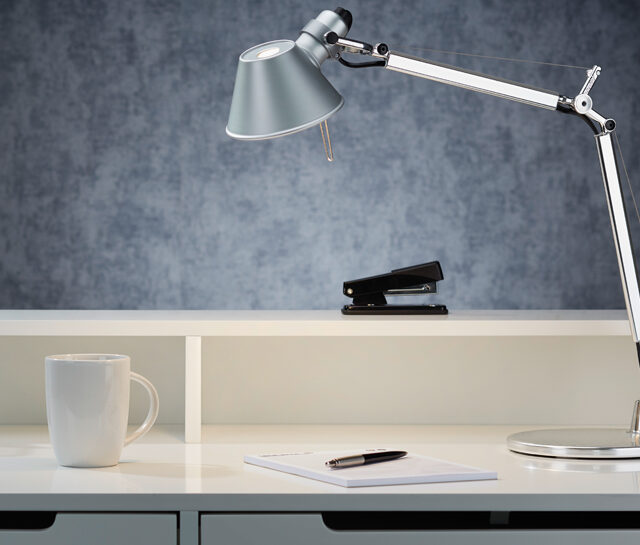 Artemide Tolomeo Mini aus Aluminium im Ambiente auf einem Schreibtisch mit Tacker Tasse und Büroutensilien